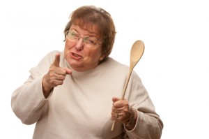 Upset Senior Woman with The Wooden Spoon Isolated on a White Background.